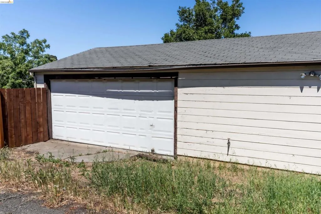 Spacious detached garage offering over 600 sq. ft., featuring horizontal siding and a panel-style garage door. Conveniently accessed through a shared alley