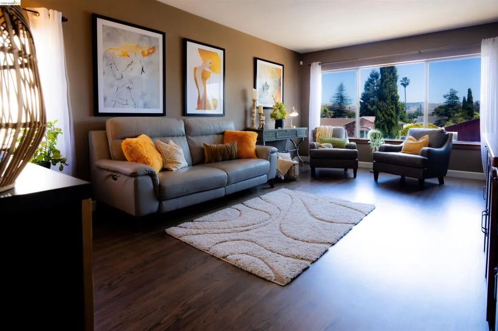 Spacious living area featuring large picture windows, wood-finish flooring, and a neutral color palette