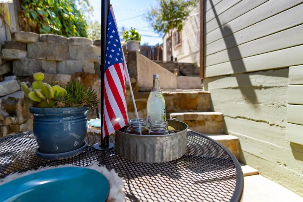 Outdoor patio area featuring a metal mesh table, a stone retaining wall, and concrete steps