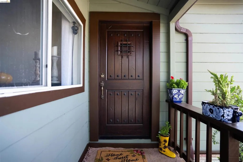 Entryway featuring a dark wood door with decorative ironwork and stud detailing. Kitchen window looking unto porch with a view of the Vallejo hills.