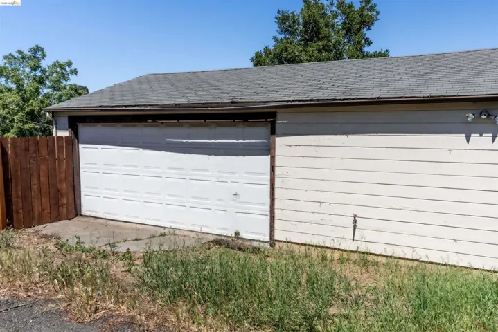 Spacious detached garage offering over 600 sq. ft., featuring horizontal siding and a panel-style garage door. Conveniently accessed through a shared alley