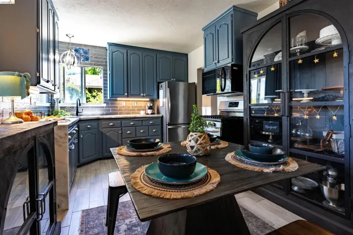 Kitchen featuring blue cabinetry, brick-patterned backsplash, and stainless steel appliances