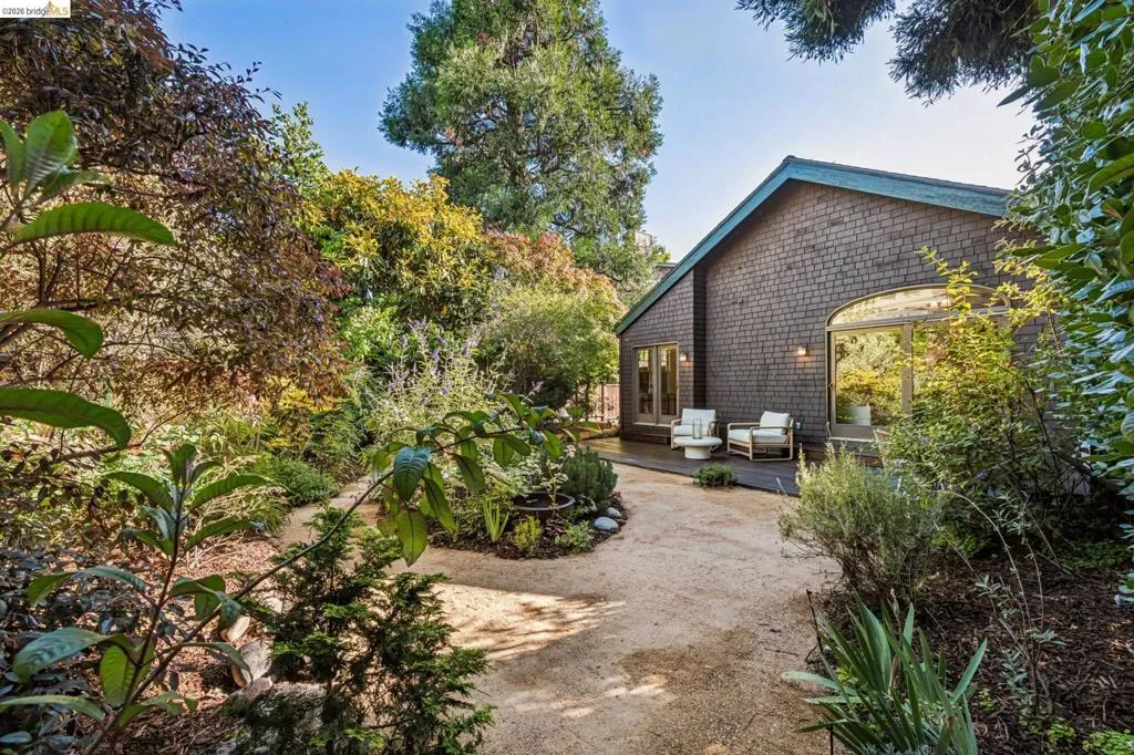 Exterior featuring shake siding, an arched window, and a private patio