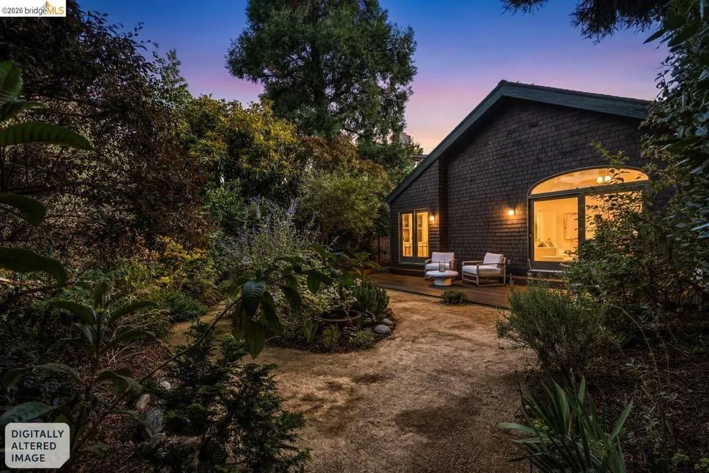 Shingle-sided exterior featuring an arched window and glass doors opening to an outdoor patio