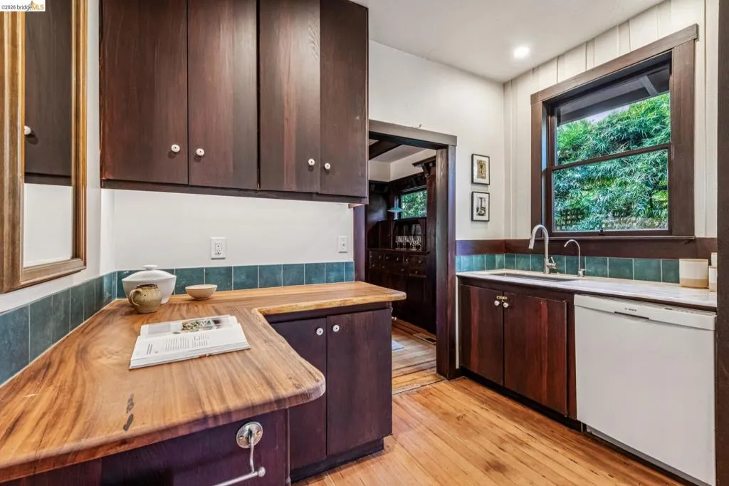 Kitchen featuring rich wood-finish cabinetry, solid wood countertops, and a tile backsplash