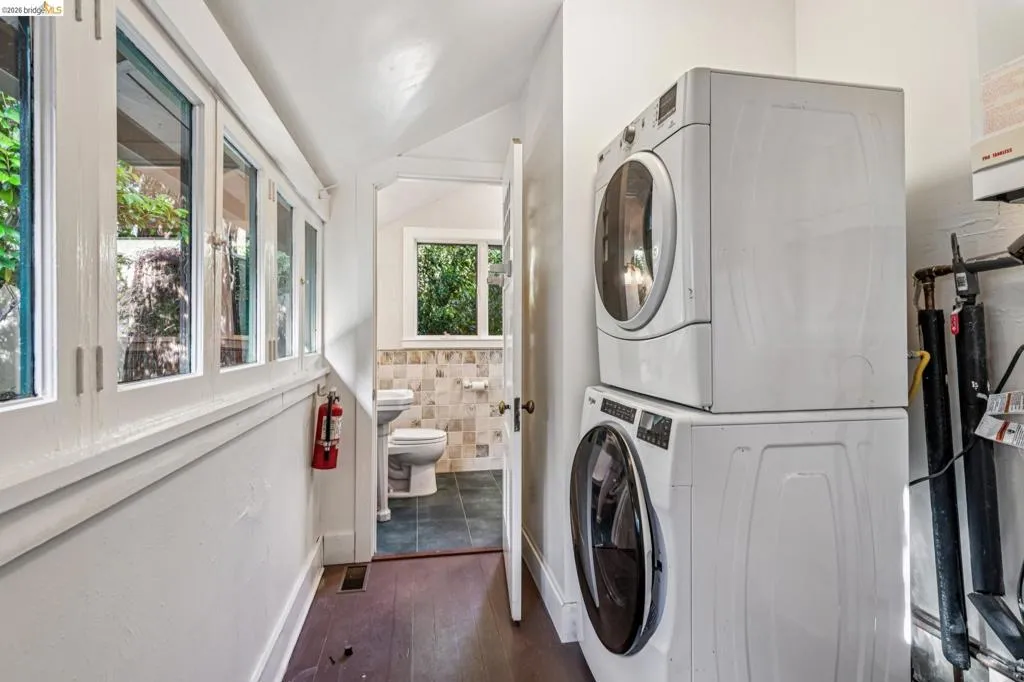 Dedicated laundry area with a stacked washer and dryer, featuring wood-finish flooring