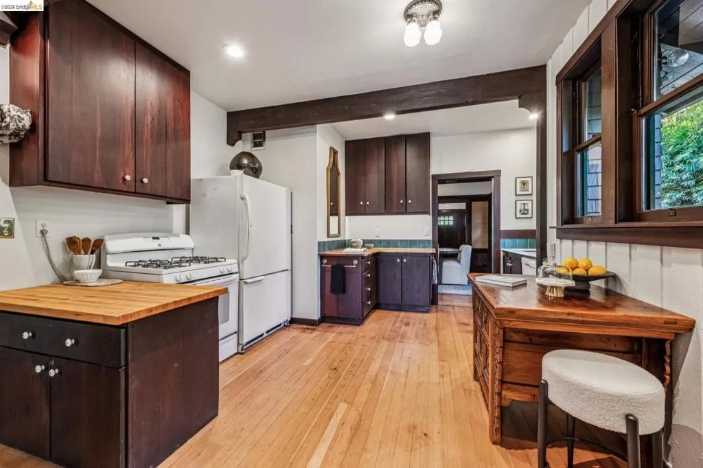 Kitchen featuring wood-finish flooring, dark wood cabinetry, white appliances, and a wood-top island