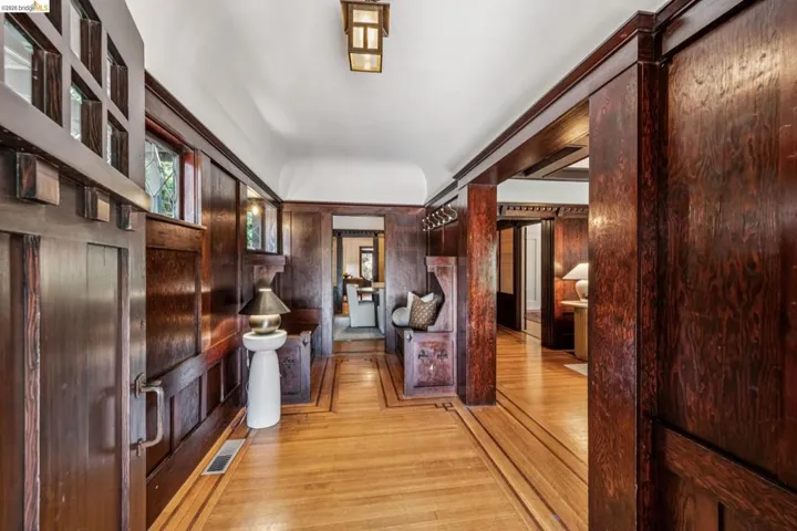 Entryway featuring stunning original rich wood paneling, hardwood flooring with decorative inlay, transom windows, and a built-in bench.