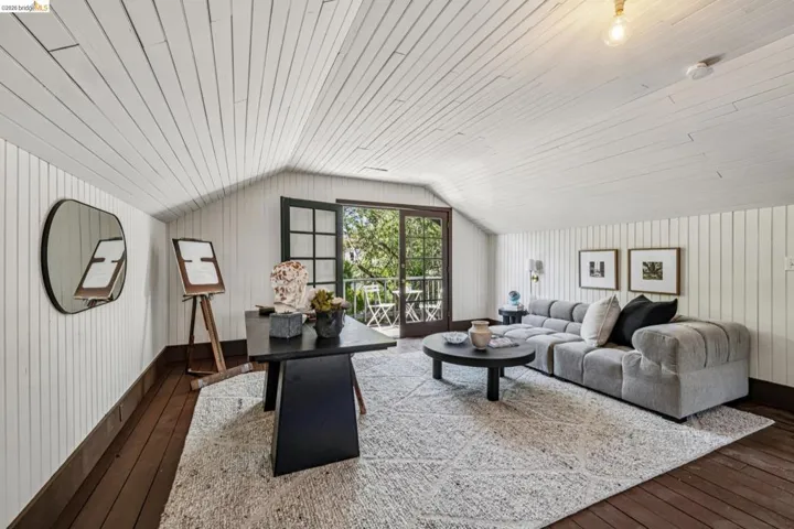 Attic space featuring pitched white plank ceilings, wood-finish flooring, and white vertical plank walls