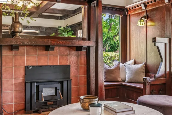 Built-in fireplace with a terra cotta tile surround and a substantial wood mantel and built-in seating on either side.