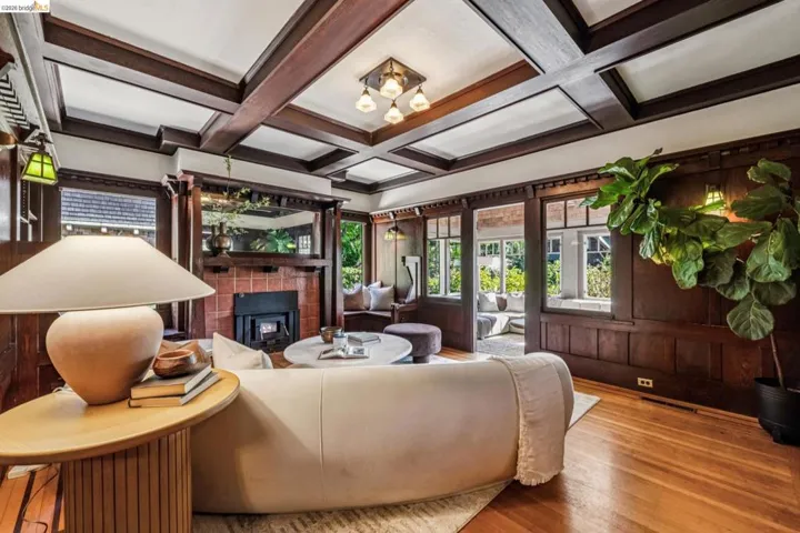 Living area featuring an exposed wood beam ceiling, wood-paneled walls, and wood-finish flooring