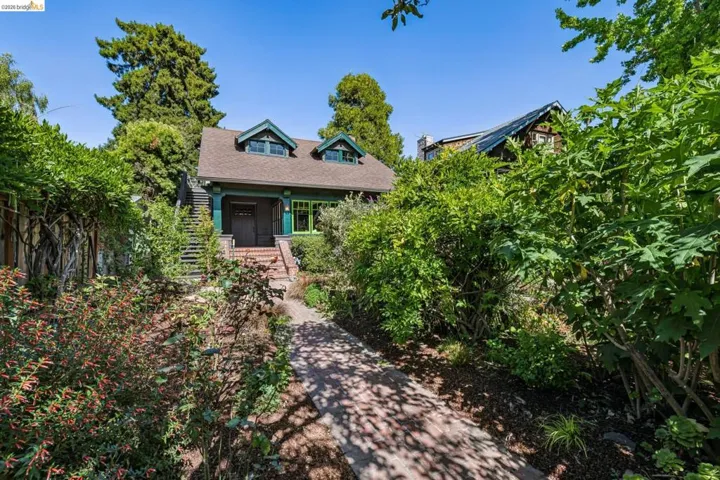 Craftsman-style home featuring a brown shingle roof with dormer windows, a covered front porch, and a brick staircase