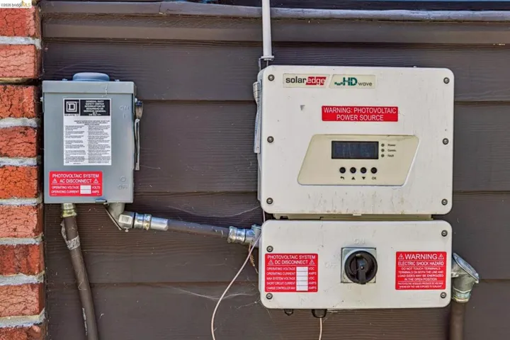 Photovoltaic power source with an HD Wave inverter system, featuring an AC disconnect and a DC disconnect mounted on exterior siding with brickwork