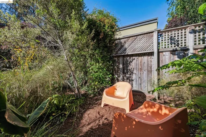 Private outdoor space featuring established trees, varied foliage, and a wood privacy fence with lattice detailing
