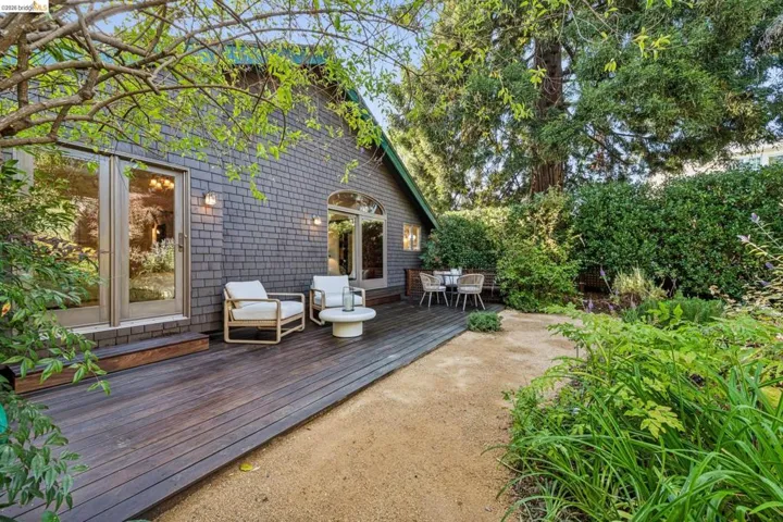 Dark wood-finish decking complementing the shingle-clad exterior, featuring double glass doors and an arched window