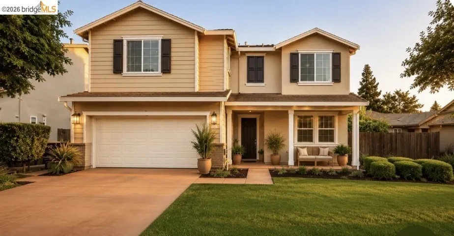Two-story residence featuring a two-car garage, covered entry porch, dark shutters, and a manicured front lawn