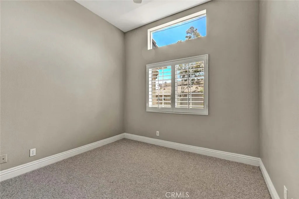 Guest bedroom featuring plantation shutters and newly installed carpet.