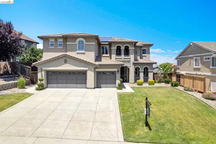 Stucco exterior featuring arched windows, a multi-car garage, and a concrete driveway