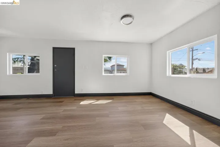 Room featuring wood-finish flooring, white painted walls, and dark baseboards