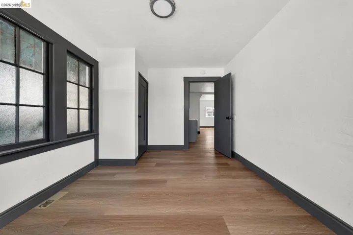 Hallway featuring wood-finish flooring, white walls, dark trim, and multiple windows with divided lites