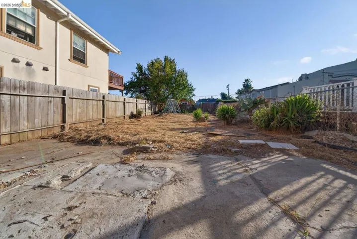 Concrete patio area extending to a spacious yard with established perimeter fencing