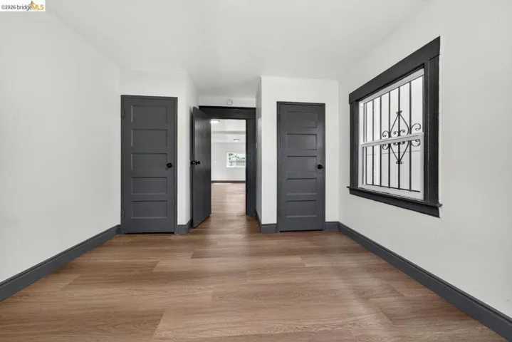 Interior room featuring wood-finish flooring, white walls, and dark trim