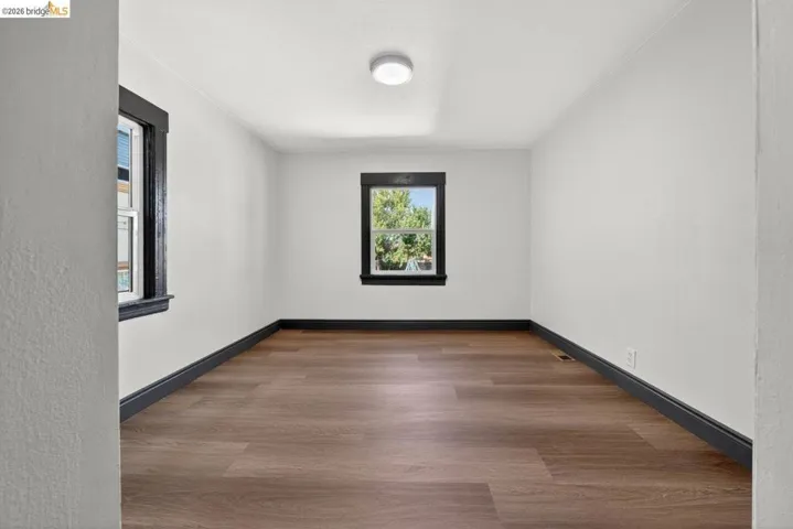 Bright room featuring wood-finish flooring, white walls, and dark trim