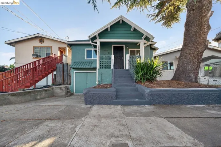 Teal-painted stucco exterior with a covered front porch, concrete steps, and an attached garage
