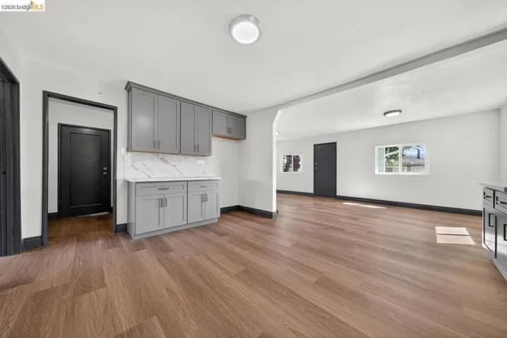 Open-concept living space featuring wood-finish flooring, white walls, and dark trim