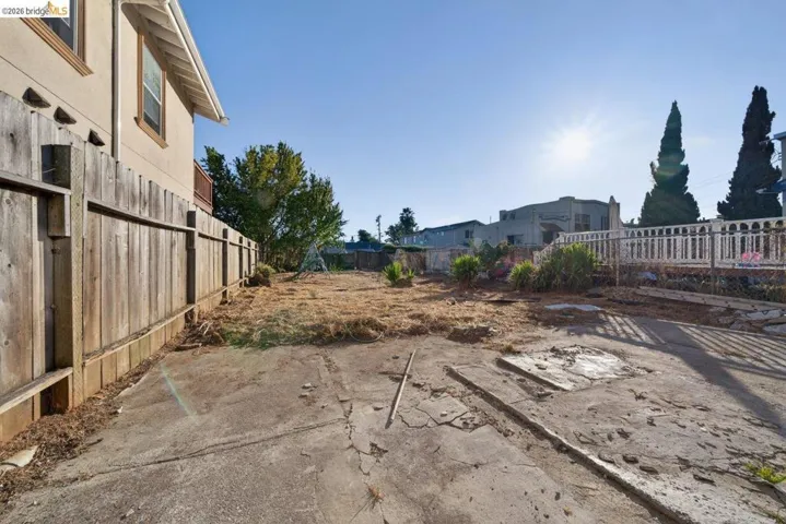 Expansive lot featuring concrete ground cover and a wooden privacy fence