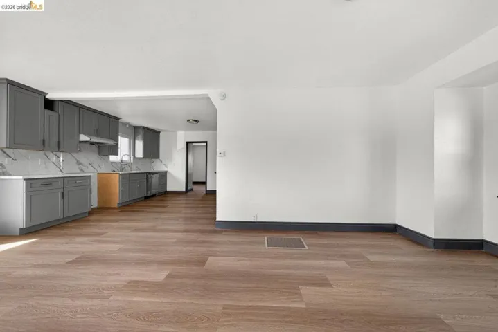 Open-concept living area with wood-finish flooring, white walls, and dark baseboards