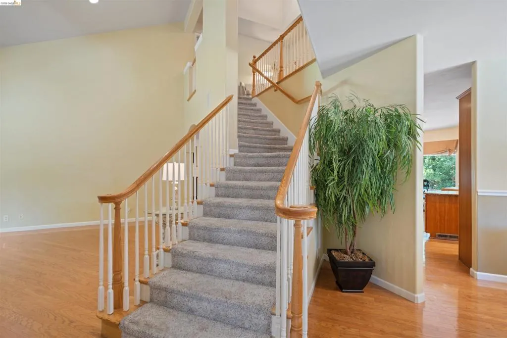 Carpeted staircase with light wood handrails and white balusters