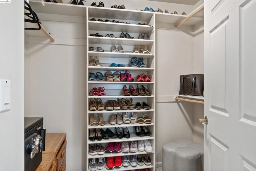 Walk-in closet featuring extensive built-in shelving, multiple hanging rods, and a light-colored wood-finish drawer unit