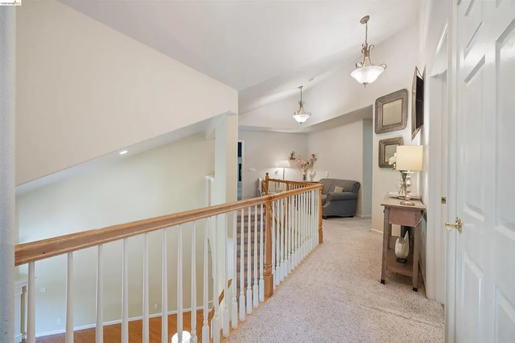 Upper-level landing featuring vaulted ceilings, carpeted flooring, and white paneled doors