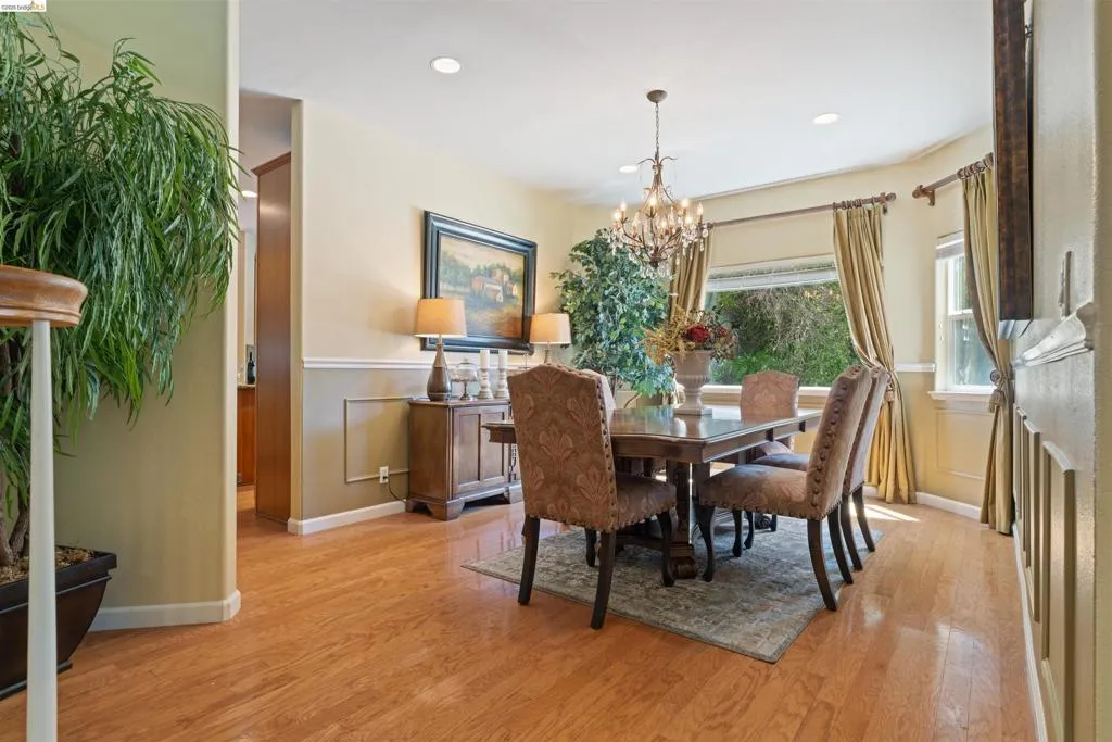Dining area featuring wood-finish flooring, a bay window, recessed lighting, and a chandelier
