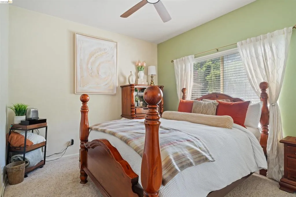 Carpeted bedroom featuring a vaulted ceiling with a ceiling fan, a window with blinds and drapes, and a two-tone wall color scheme