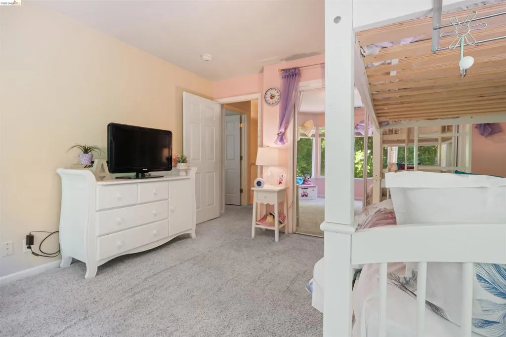 Wall-to-wall carpeting and a neutral wall color define this room, featuring a white paneled interior door