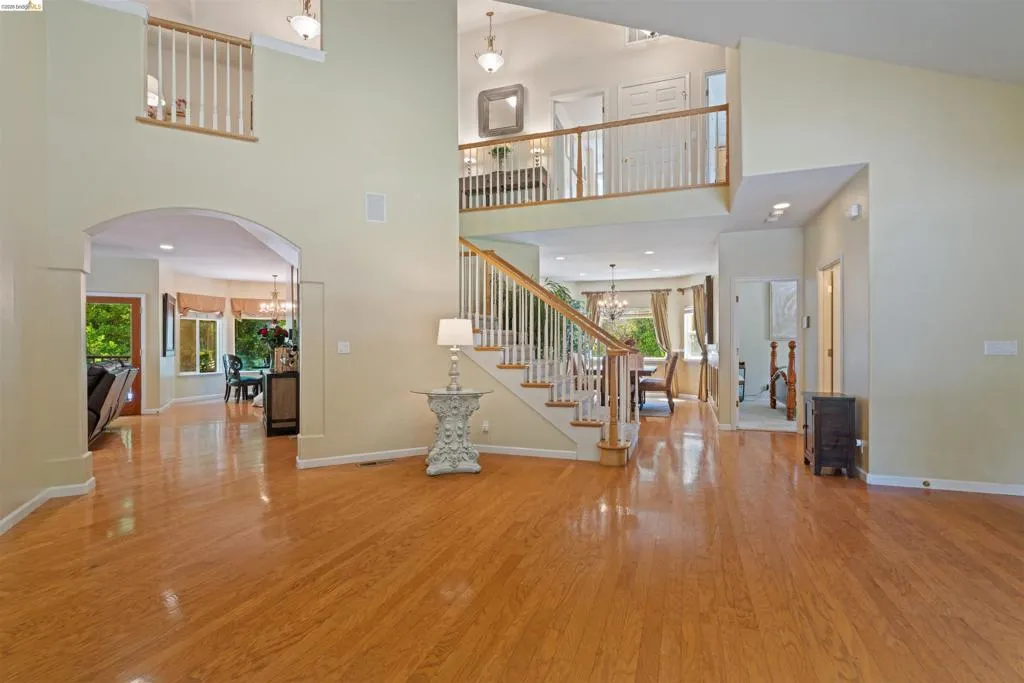 Expansive entry foyer featuring wood-finish flooring, a grand staircase with white balusters, and a second-story balcony