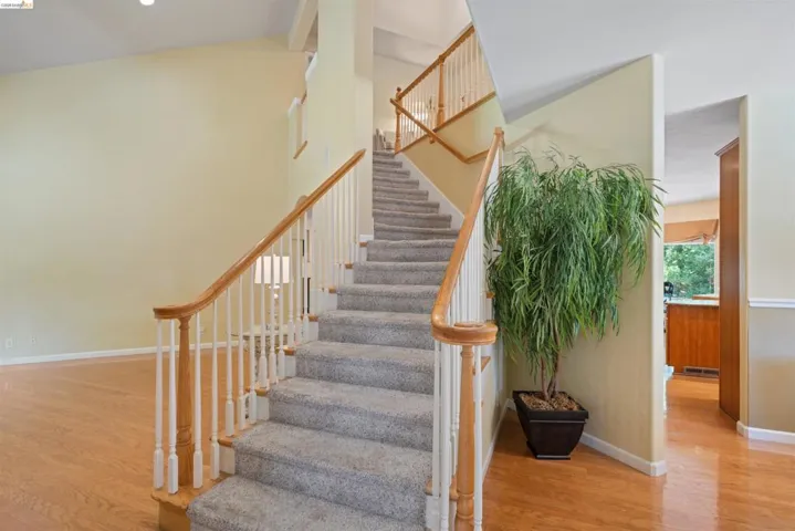 Carpeted staircase with light wood handrails and white balusters