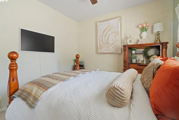 Bedroom featuring a built-in wall-mounted television and a wood-finish ceiling fan