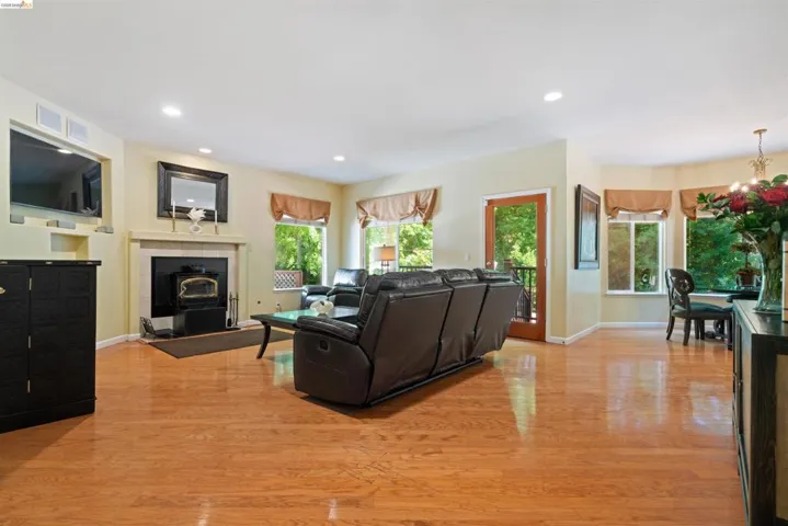Spacious living area featuring polished wood flooring, a central fireplace with an ornate mantel, recessed lighting, and multiple large windows