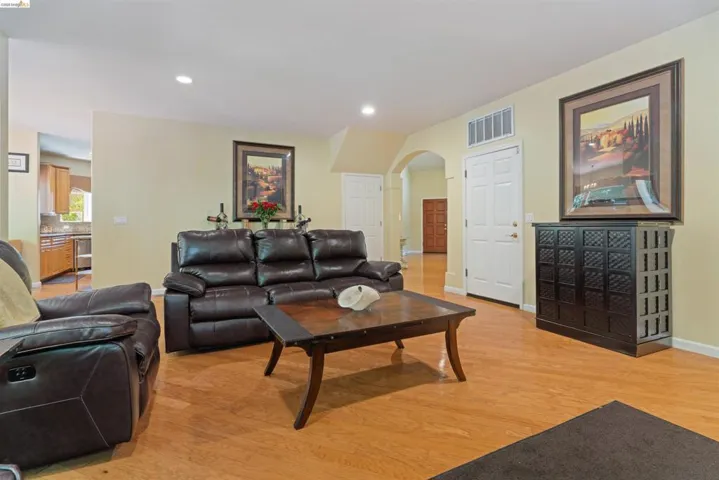 Living area featuring light wood-finish flooring, recessed ceiling lighting, a cased opening, and a built-in storage cabinet