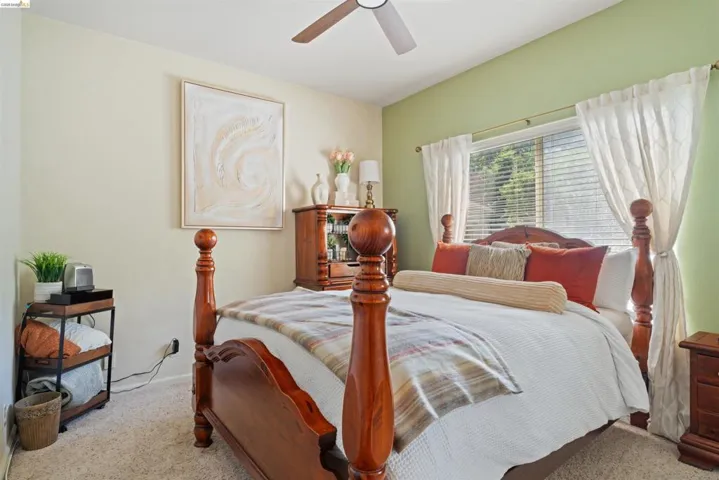 Carpeted bedroom featuring a vaulted ceiling with a ceiling fan, a window with blinds and drapes, and a two-tone wall color scheme