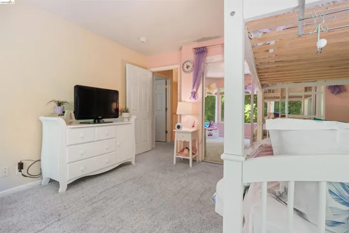 Wall-to-wall carpeting and a neutral wall color define this room, featuring a white paneled interior door