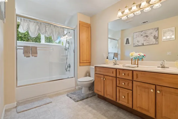 Double vanity with wood-finish cabinetry, white countertops, and dual basin sinks