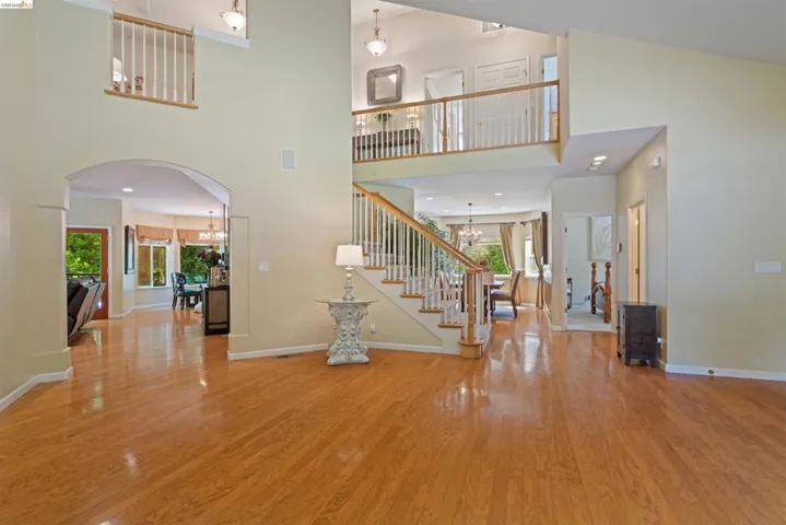 Expansive entry foyer featuring wood-finish flooring, a grand staircase with white balusters, and a second-story balcony