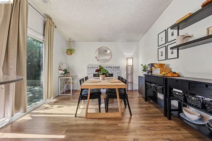 Open-concept living area featuring wood-finish flooring, a white brick fireplace, and sliding glass doors to the exterior