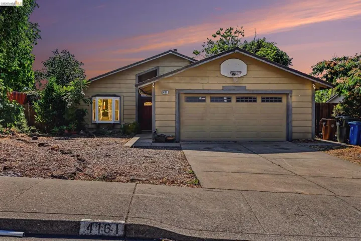 Front exterior featuring a two-car garage with a panel door, a bay window, and a gabled roofline