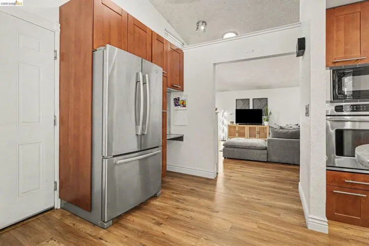 Kitchen featuring wood-finish flooring, stainless steel French door refrigerator, and wood cabinetry