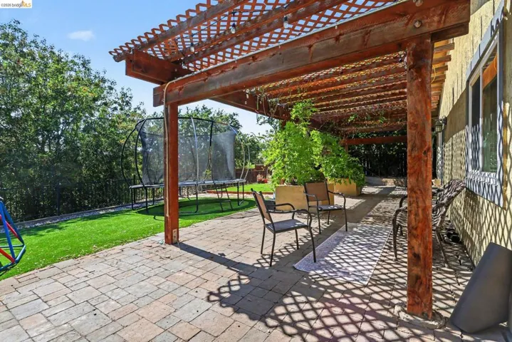 Expansive paver patio featuring a wooden pergola with lattice detailing